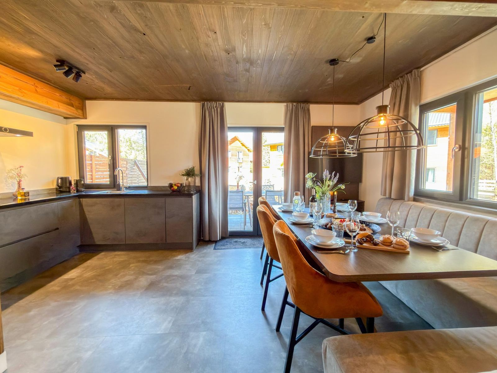 Open-plan kitchen and dining room with set table, dark-grey cabinetry and terrace doors