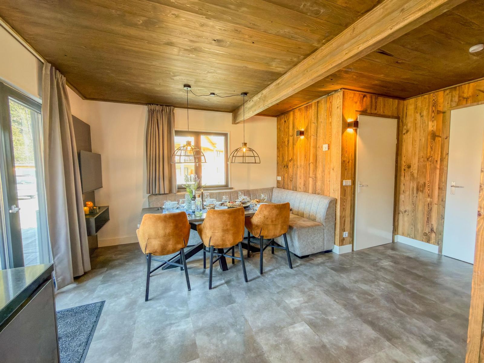 Open living and dining area with timber walls, dining table, built-in bench and sofa corner