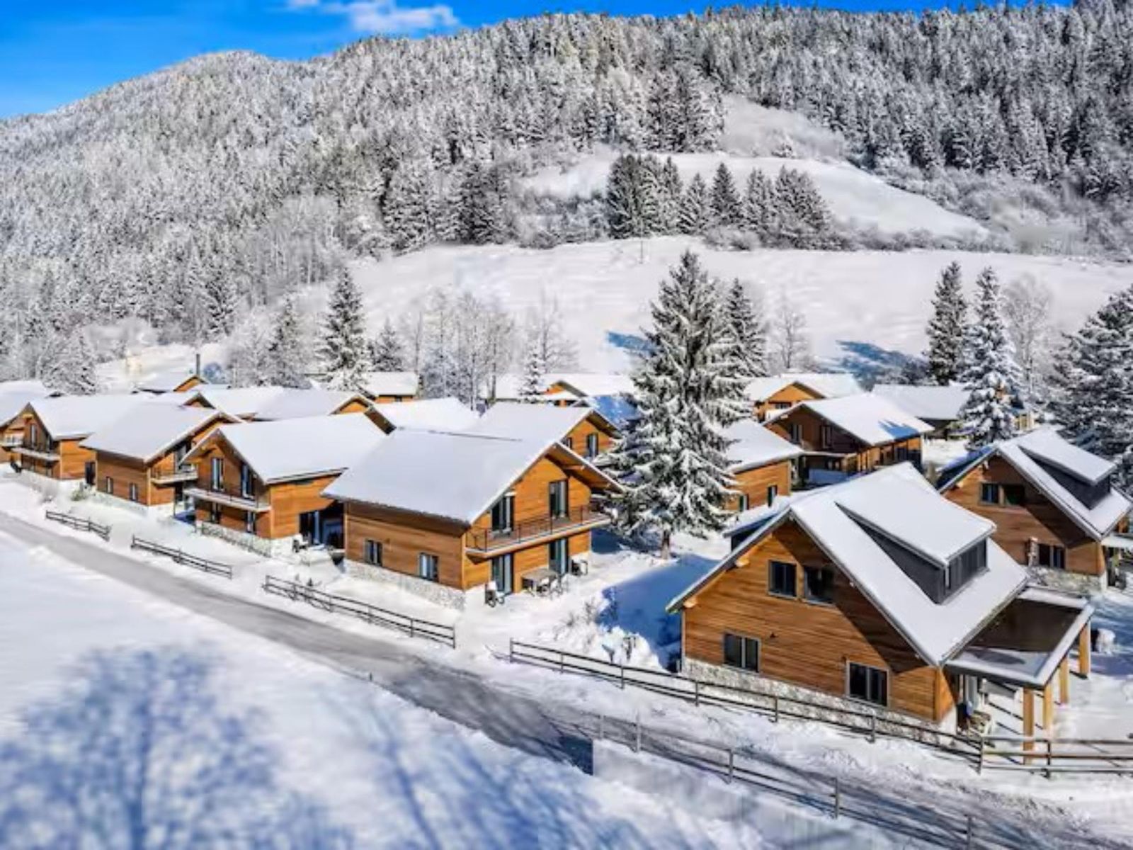 Aerial view of the snow-covered chalet park with snowy hills behind