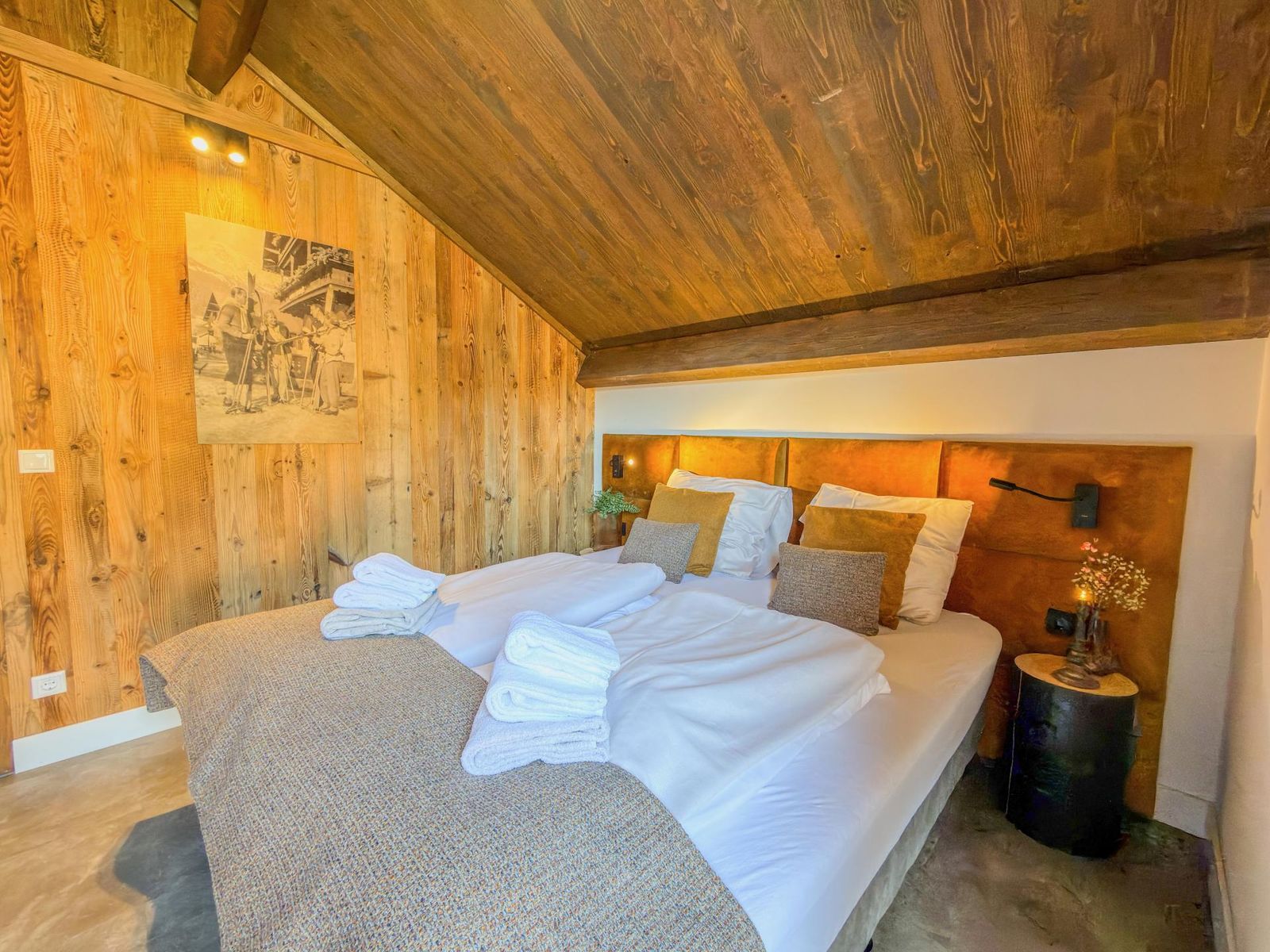 Second bedroom with two beds, bedside lighting and alpine artwork under a sloped ceiling
