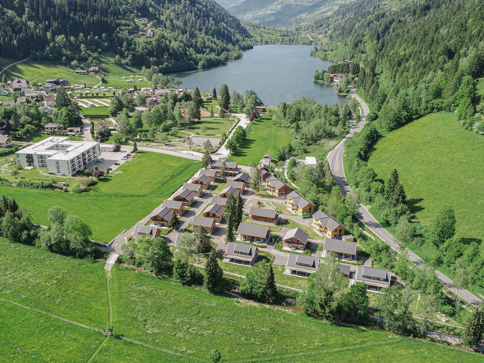 Aerial view of the chalet park with the Afritzer See and forested valley directly behind it