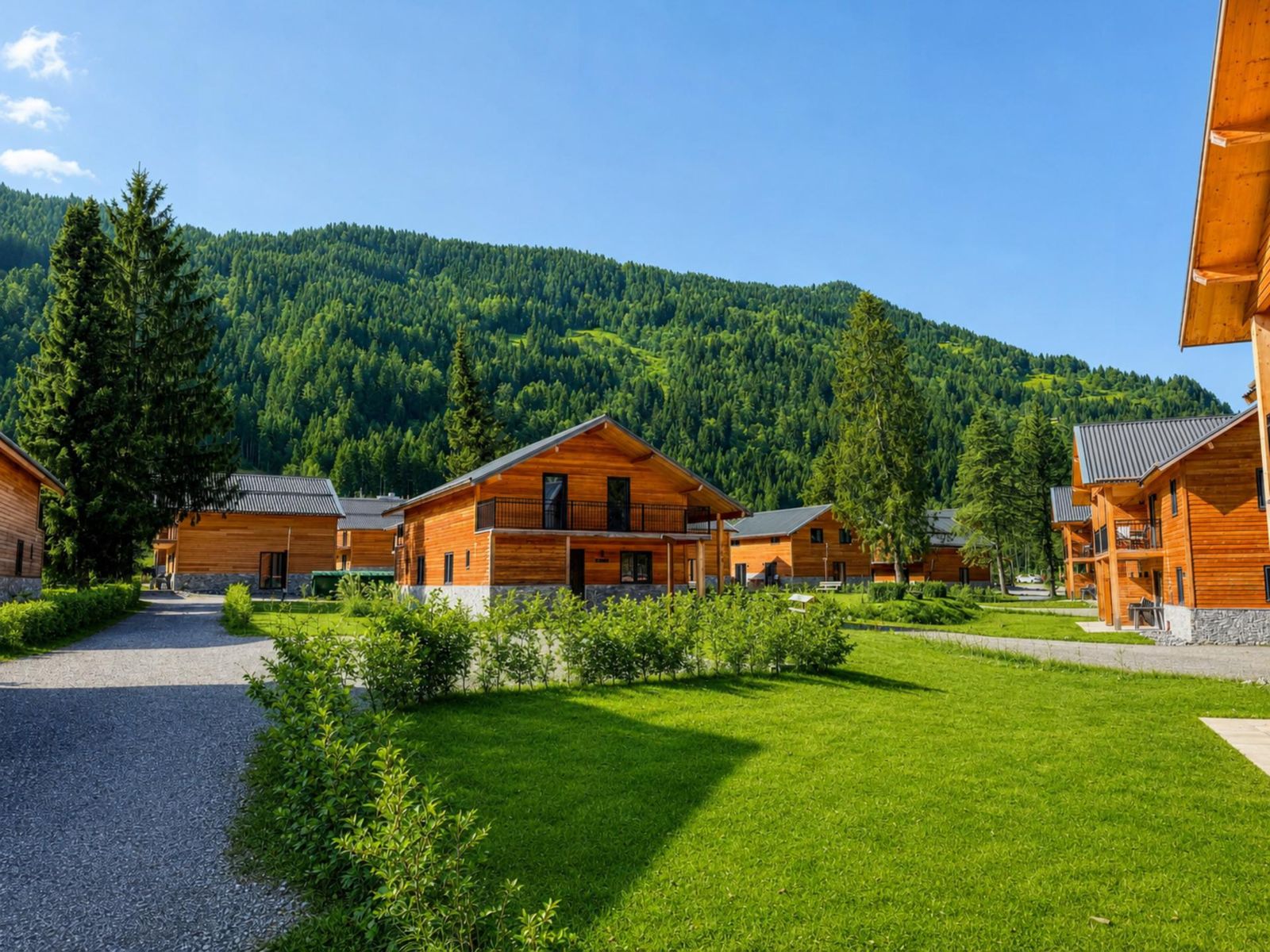 Shared green resort grounds with lawns, hedges and chalet exteriors