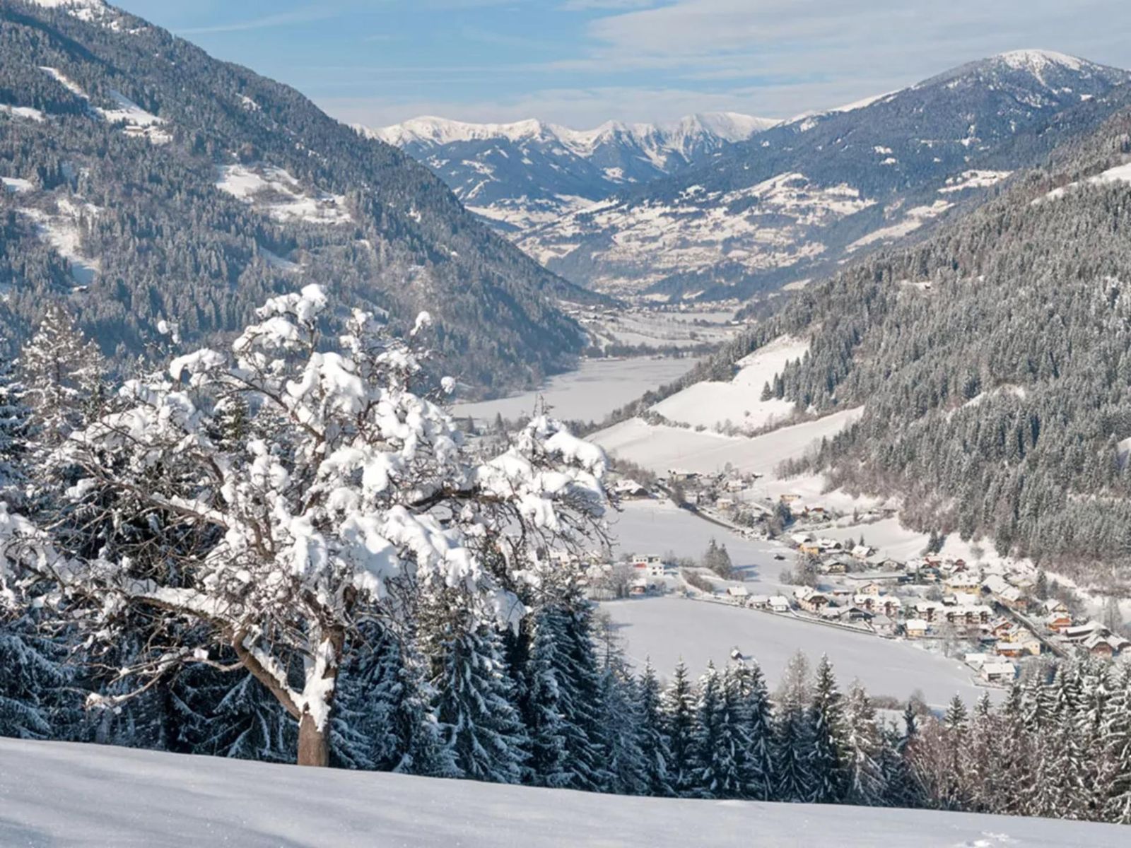 Winter panorama over a snowy valley and snow-lined lake