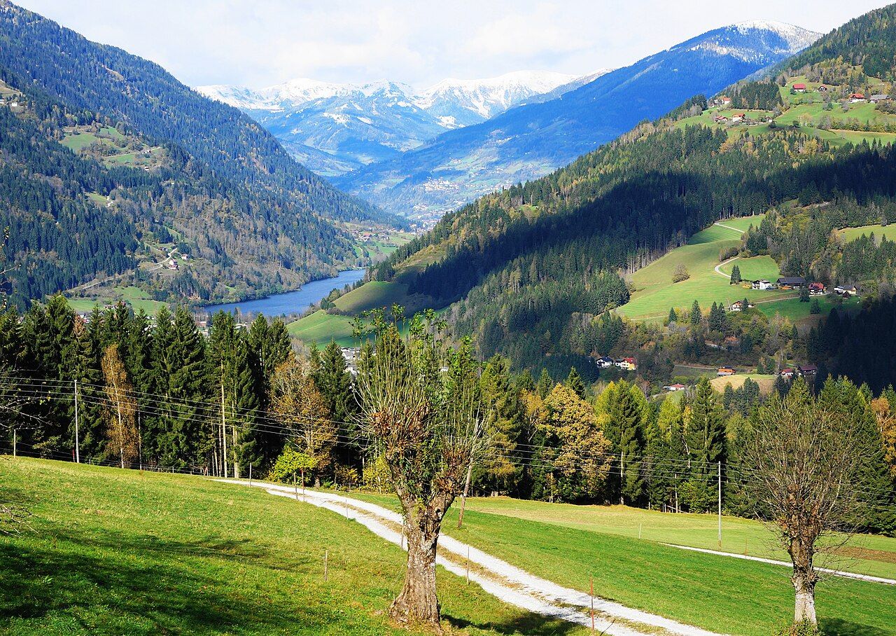 Elevated view over fields and hillside farms toward the Afritzer See and the Nockberge