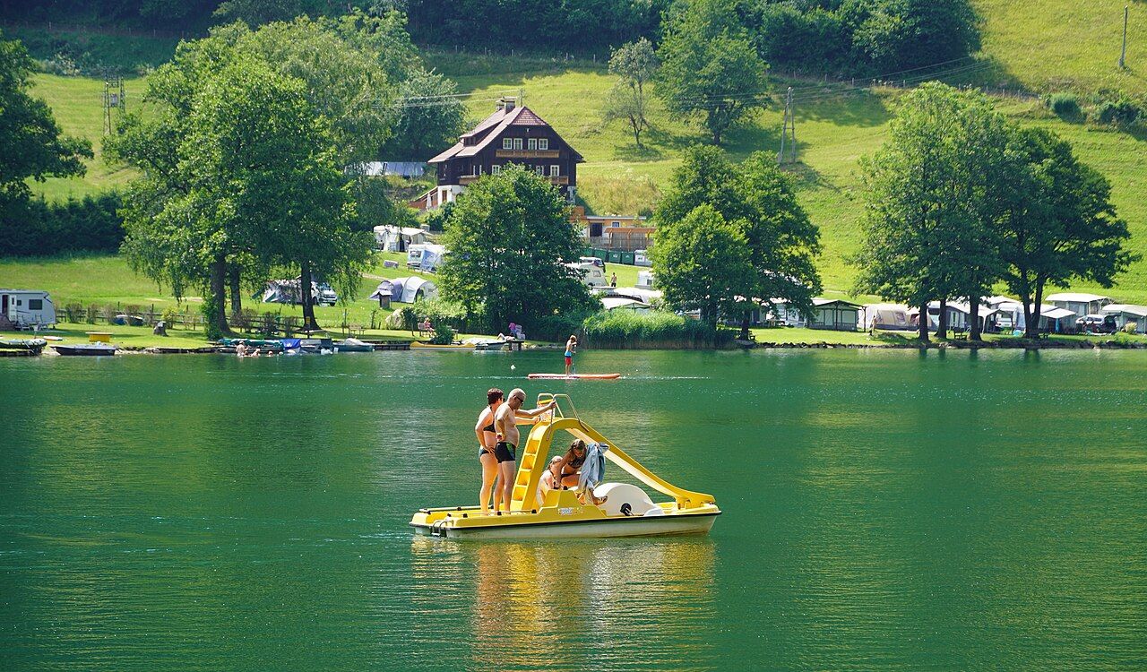 Pedal boat and paddleboarder on the Afritzer See with green shore behind