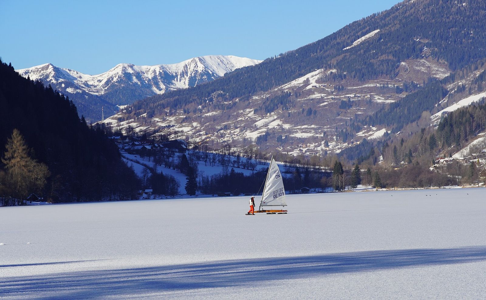 Ice sailor crossing the frozen Afritzer See with snowy Nockberge behind