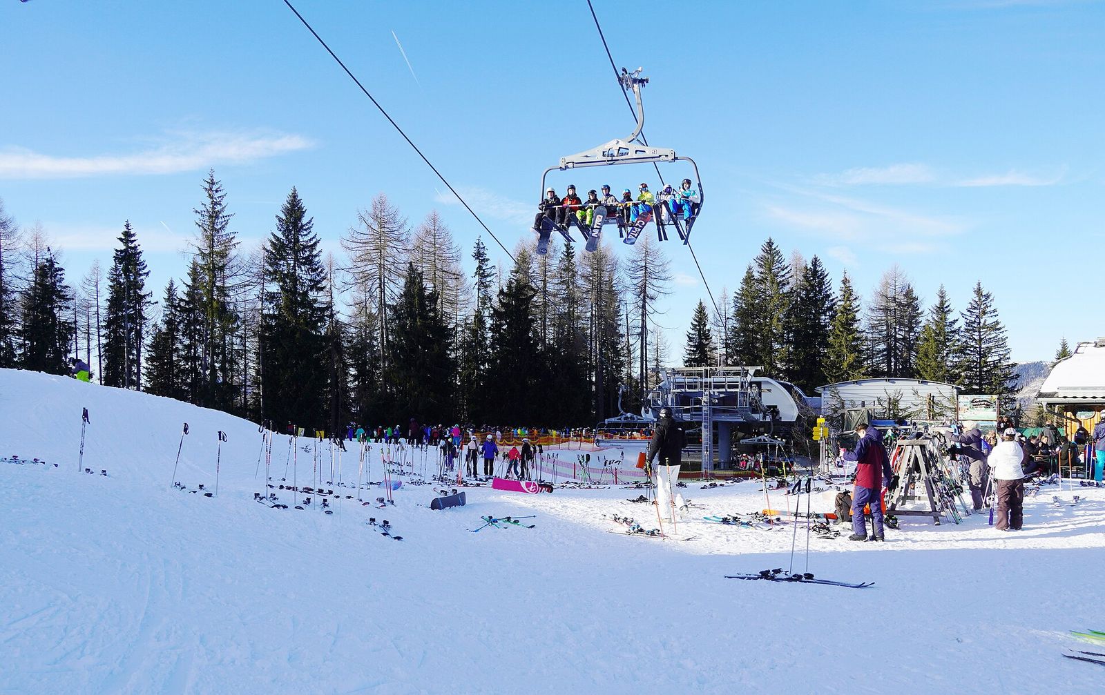 Chairlift carrying skiers over a snowy slope between trees at Gerlitzen