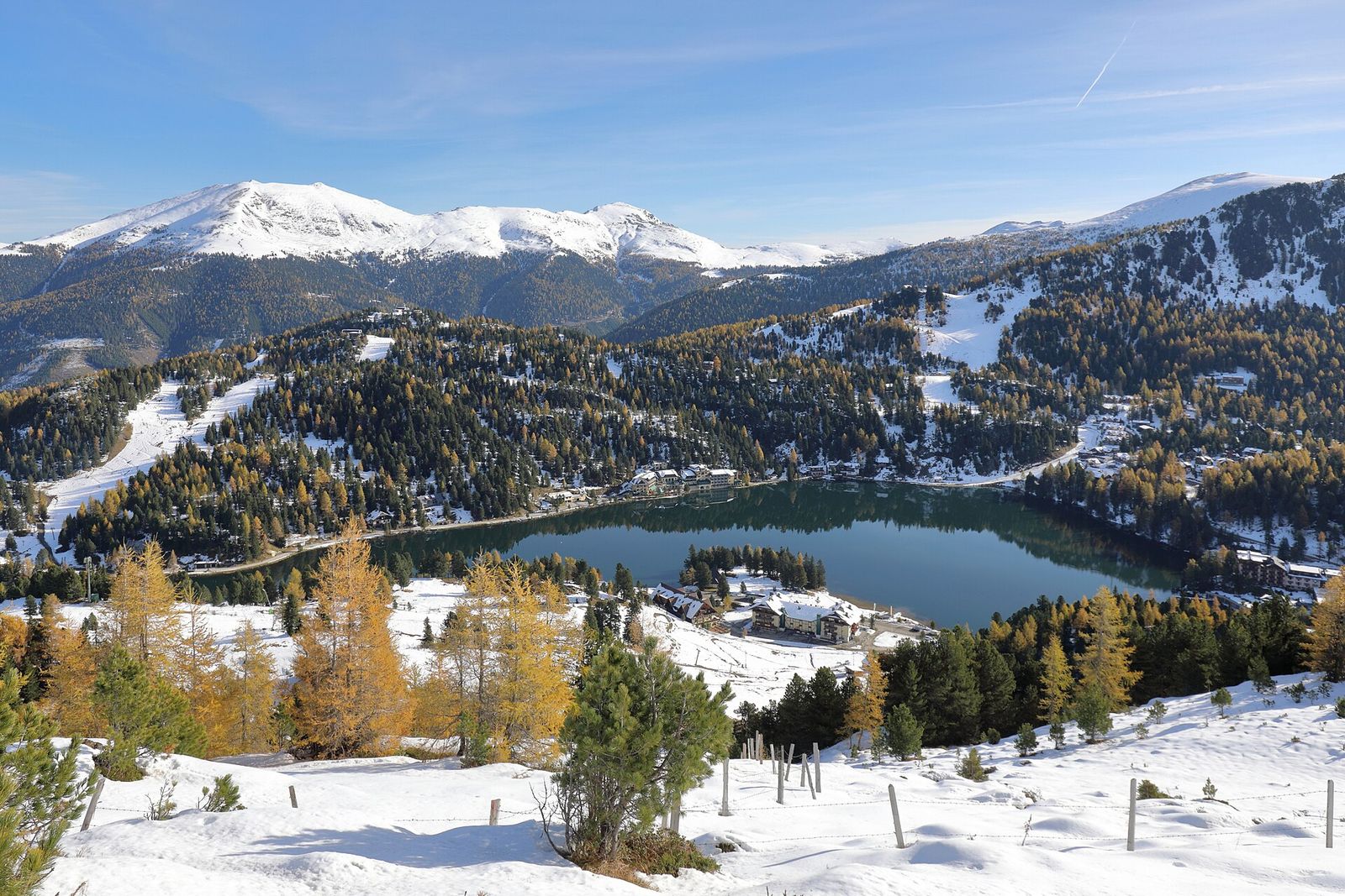 Turracher See between snow-dusted larch forests and white peaks