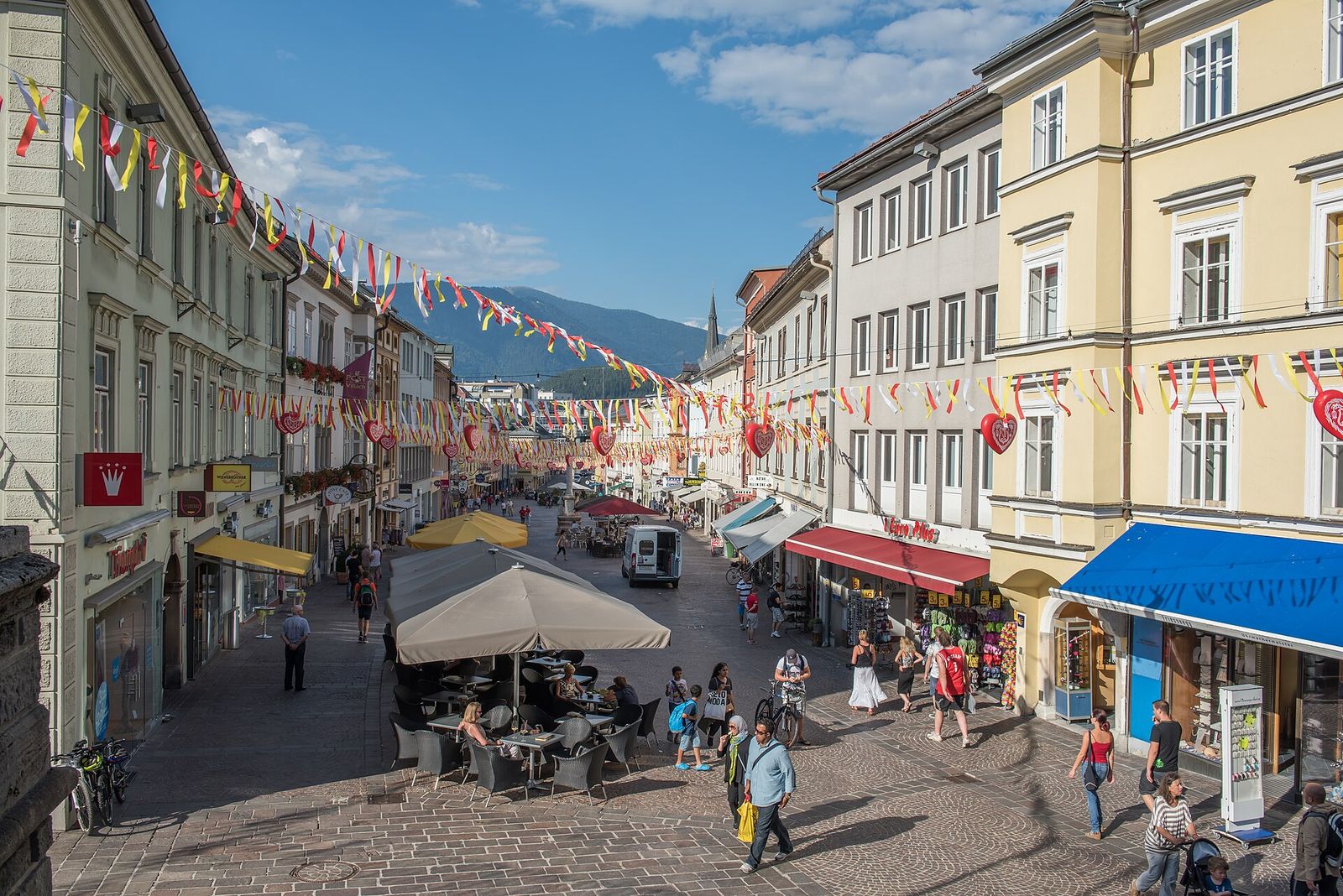 Villach old town square with pavement cafes, bunting and mountains behind